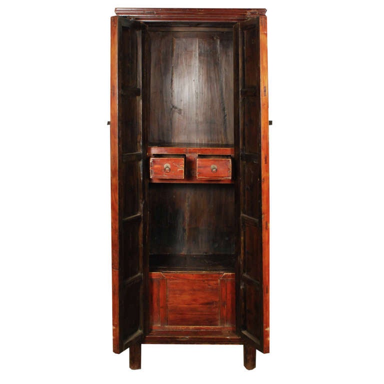 A 19th century Chinese tall and narrow red lacquered cabinet with two doors with brass hardware.