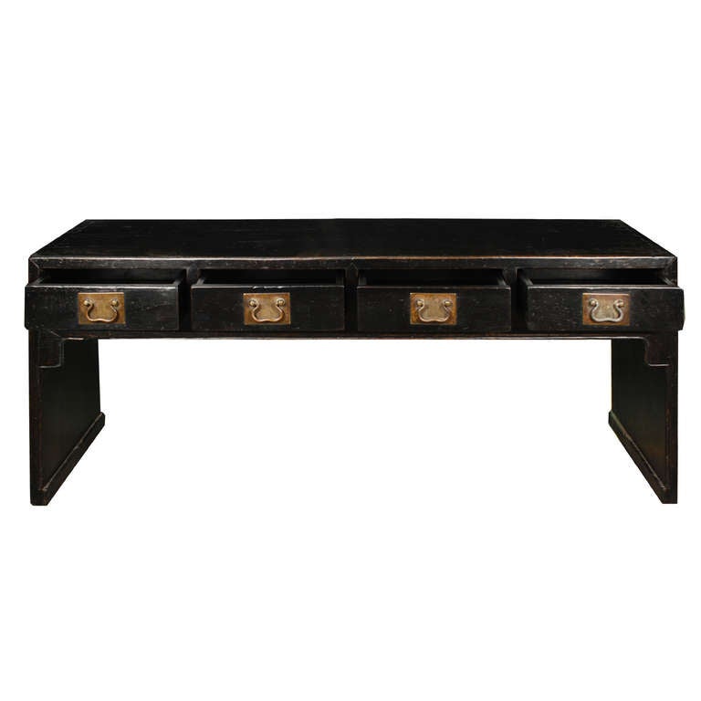 An early 20th century Chinese black lacquered elmwood low scroll table with four drawers with brass hardware.