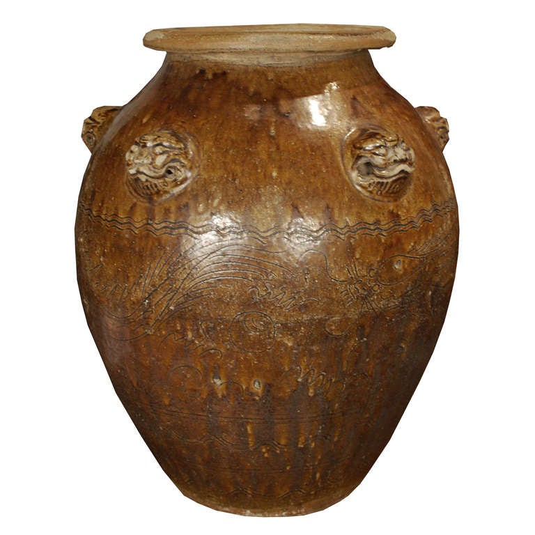 A circa 1850 brown glazed ceramic storage jar from China. The jar features fu dog handles and dragon etchings.<br />
<br />
