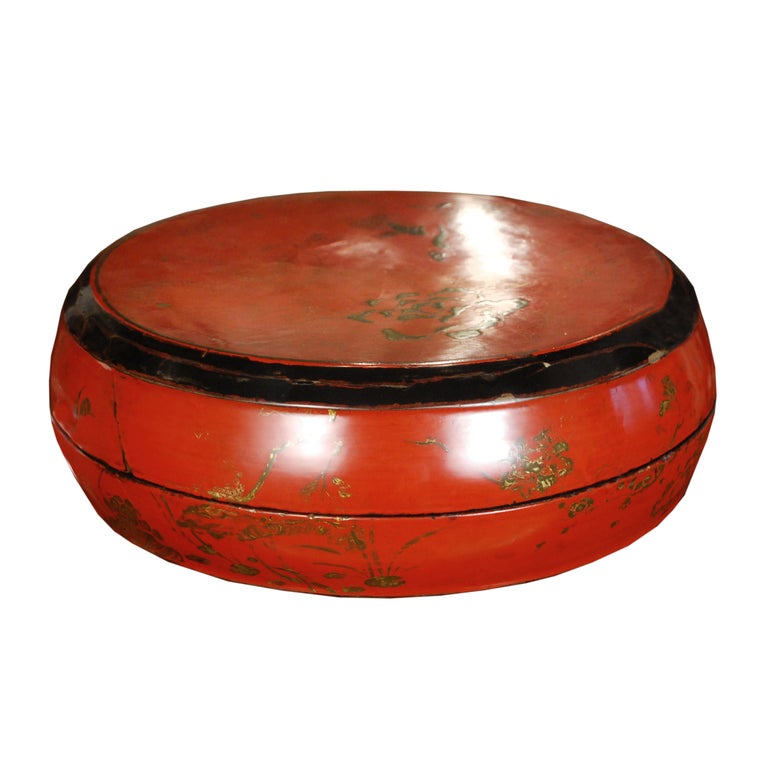 A 19th century Chinese round red lacquered wood box with painted and gilt peonies.