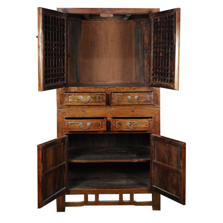 A two piece stacking cabinet from China, circa 1850. This elmwood cabinet has two doors and two drawers on the bottom section and two lattice doors and two drawers on the top section.