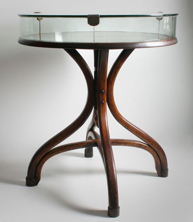 This is a wonderful piece.  The 4 inch high glass top lifts off to put your treasures in. The piece is not signed, but certainly has the quality of Thonet or Kohn.