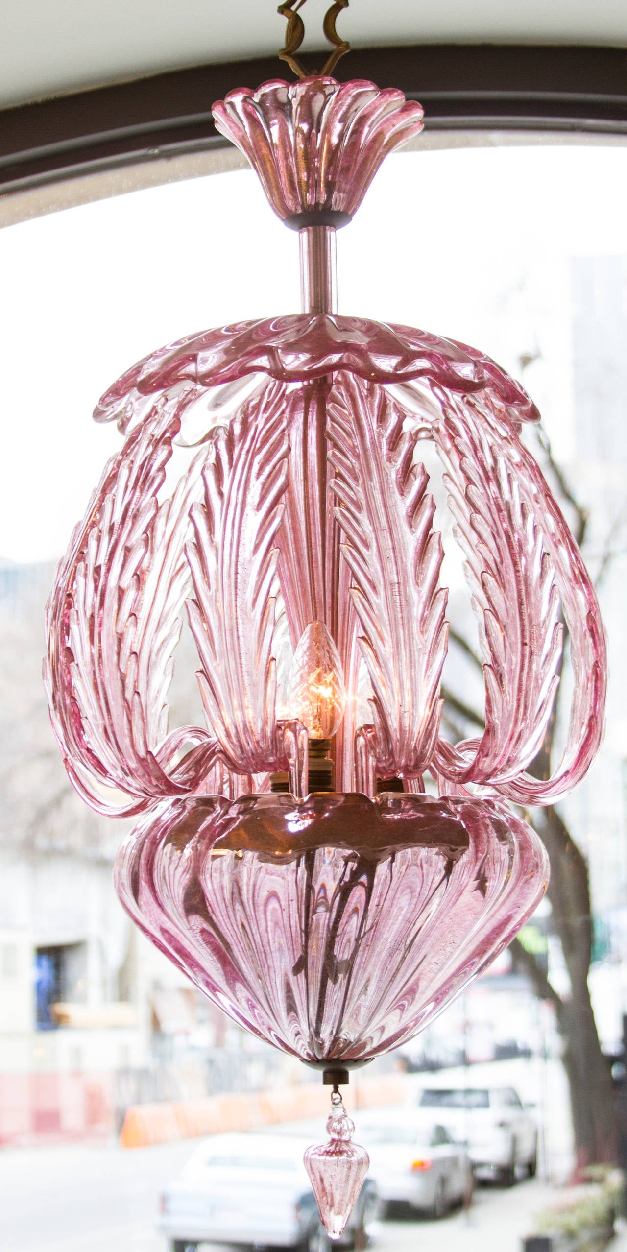 Laced with gold, This  is an unusual rose colored murano chandelier with a foliate design.  The chandelier holds four bulbs.