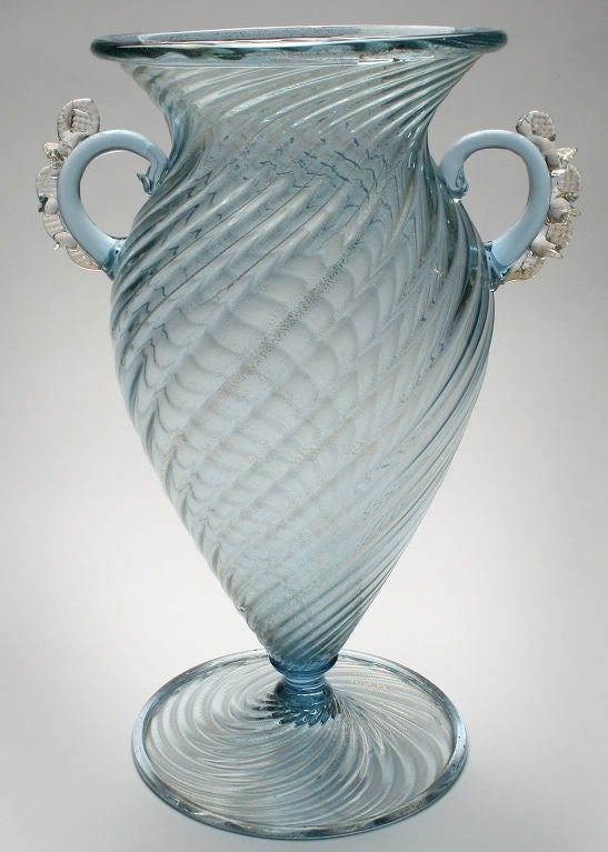 This is a very fine piece in a teal color. The design is classic and the vase is accented with two handles.