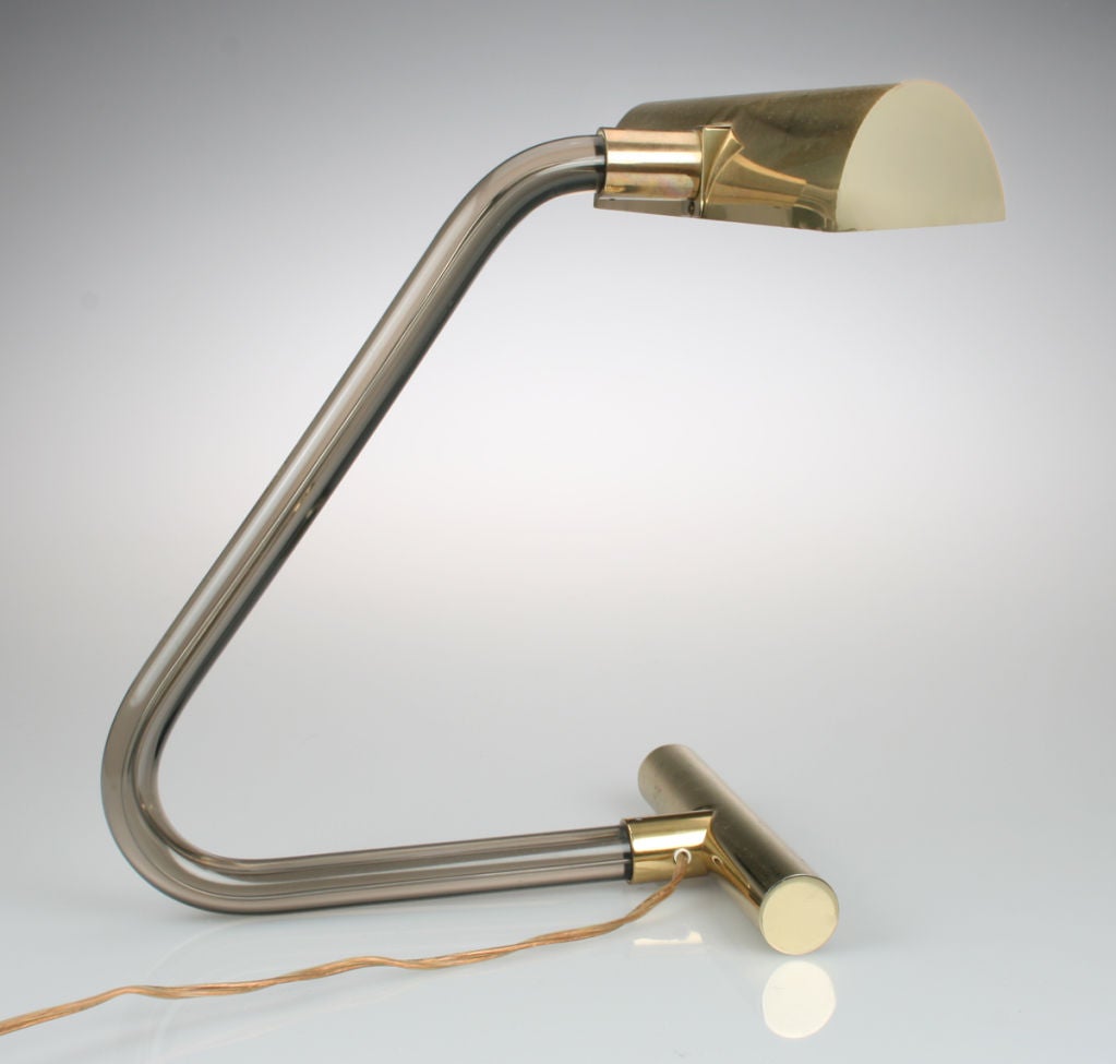 This is a clean and modern brass and smoke colored glass desk lamp. It has great lines and is good looking from any angle. The lamp takes two bulbs and has a switch in the line cord.