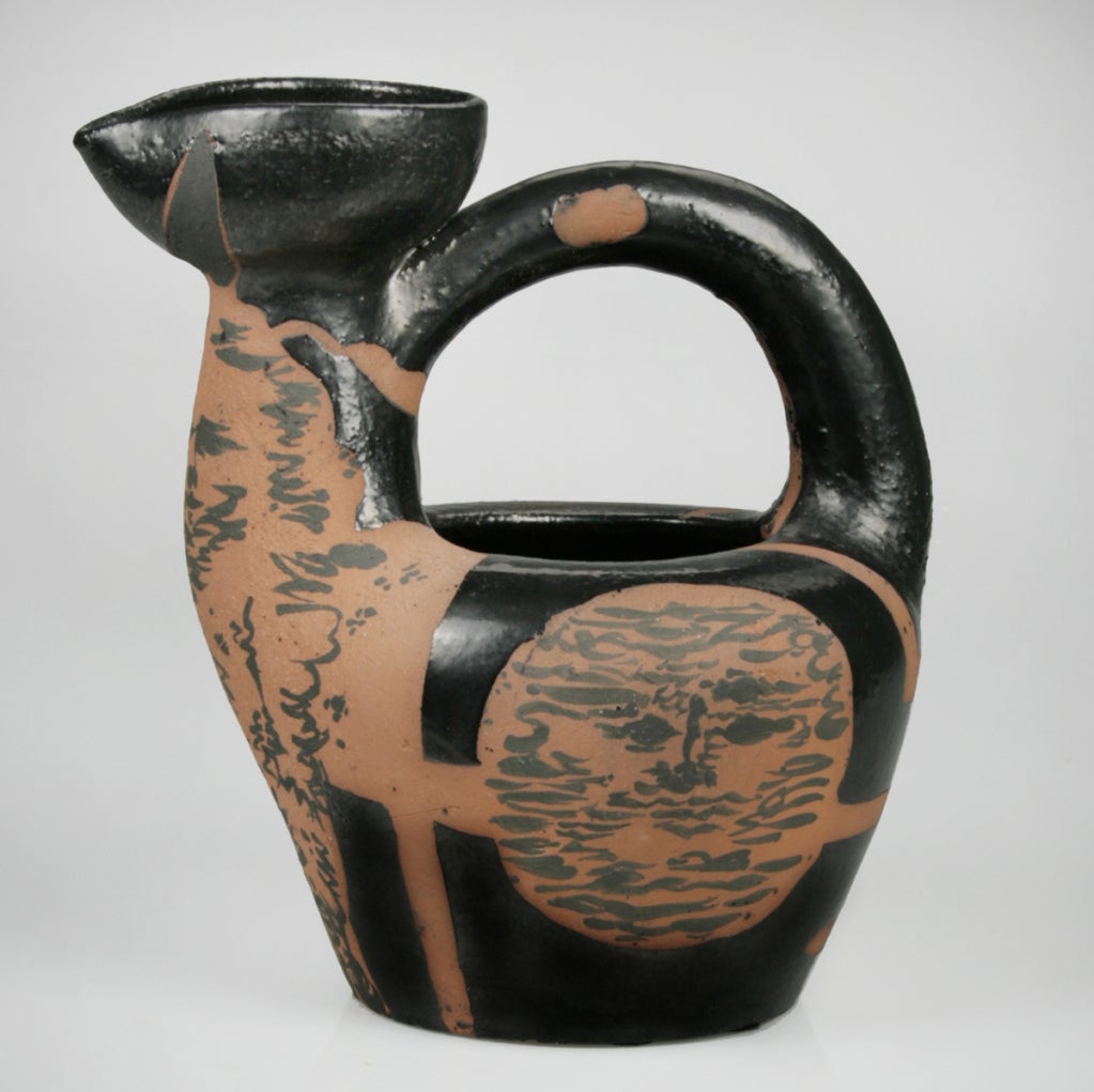 This is a  spectacular piece of ceramic art from the hands of Pablo Picasso and an early number in the edition. 
This stoneware pitcher is painted with faces on the sides and a full form on the front. The black glaze has a deep gunmetal lustre.