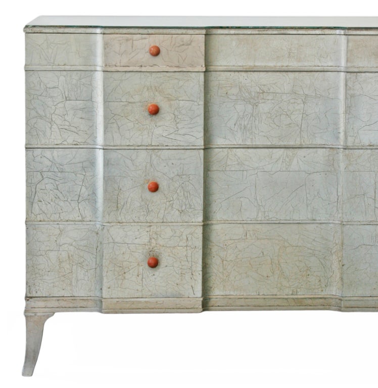 This is a very elegant Art Deco silver leafed dresser. It has eight bakelite original drawer pulls and four very large, deep drawers for storage. The beautiful silvered glass shows minimal wear. This is a striking piece of furniture called Renascene