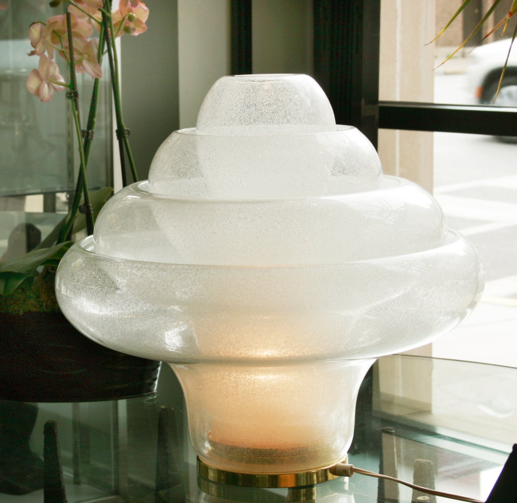 A striking sculptural lamp made of hand blown glass. 
Each bowl fits within another and is held in position with brass pins. Illuminated with one standard sized bulb.