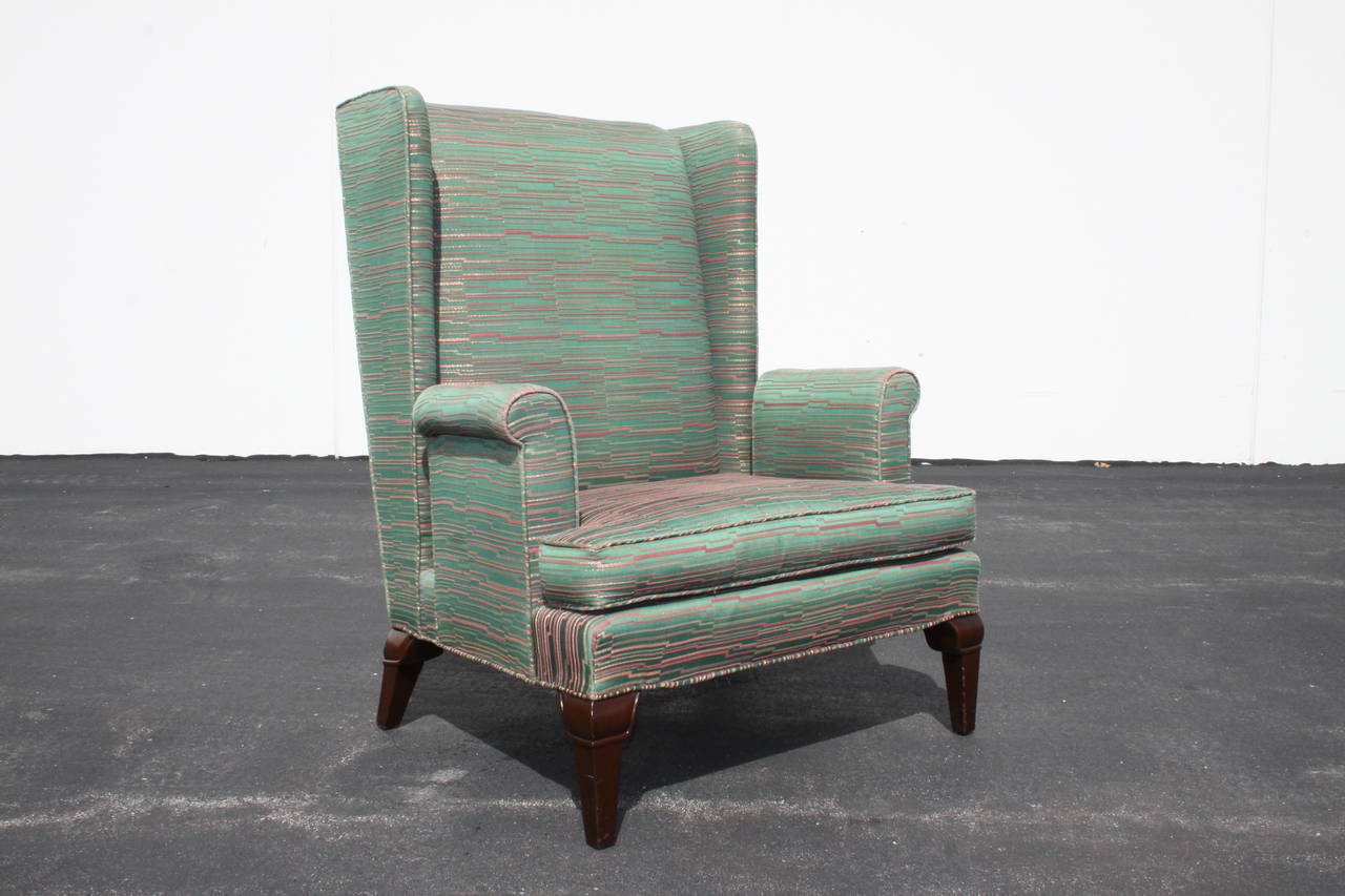 Stylish and dramatic wingback lounge chairs with splayed mahogany legs, fabric is vintage and shows wear.