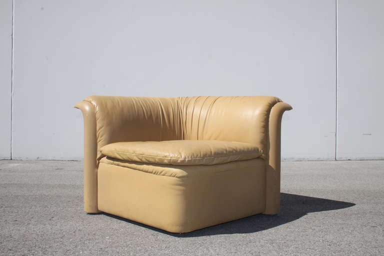 RARE Dennis Christiansen for Dunbar gold tone sculptural leather corner or wedge shape sofa chair with curved back and thin profile seat cushion, Dunbar label, circa 1970s. The plush seat is linked to the seat, with hardware.  Wear and tear to