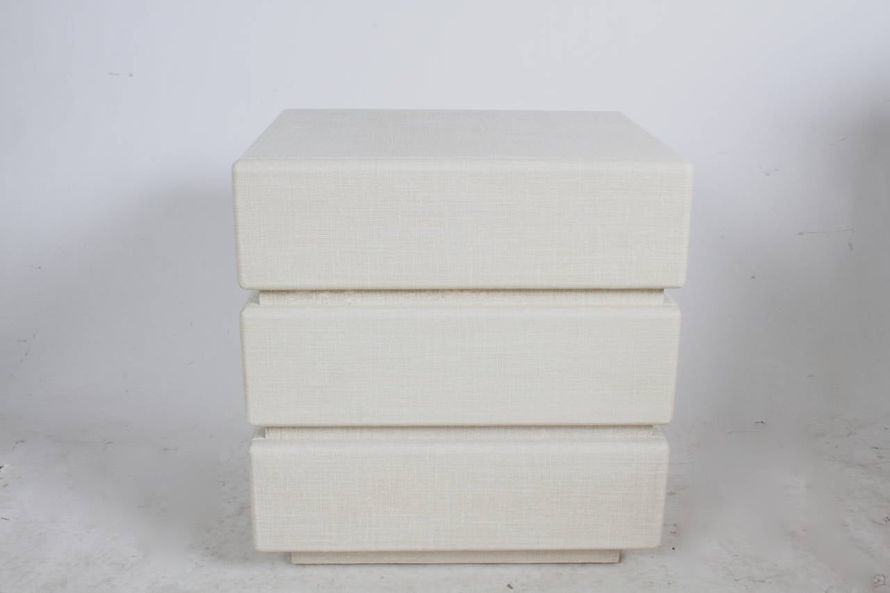 Pair of Karl Springer style night stands wrapped in linen on stepped form, alcohol resistant finish, great original condition with minor scuffs. Custom order from Randolph & Hein in the mid 80s.