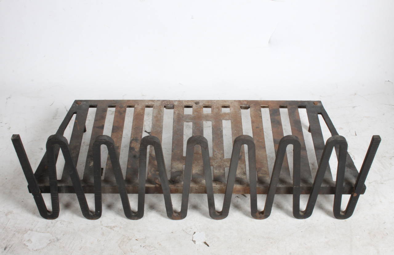 Midcentury log fireplace holder with undulating iron fire guard or fire dog that acts as Andirons. In the style of a Jean Royère, measures: 39.25 W x 17 D x 13-1/8 H.
3/4 x 3/4 thick cast metal. 
Log base 5 x 39.25 x 16-1/8.