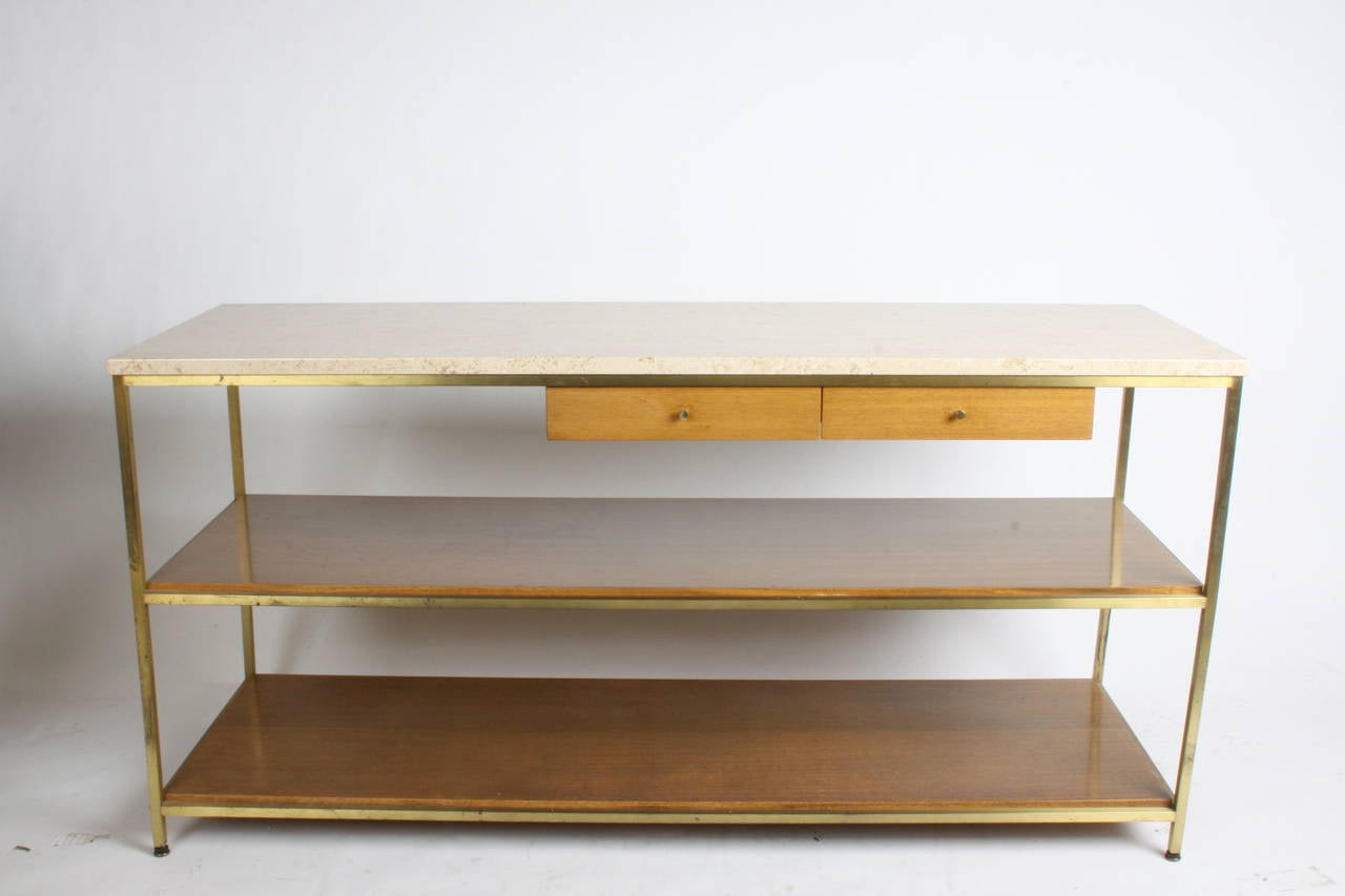 Midcentury console designed by Paul McCobb. Travertine top with two drawers and two lower shelves, brass frame, original finish