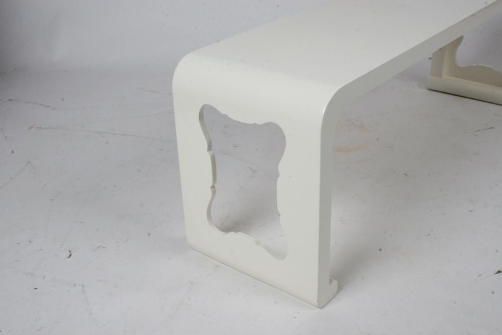 Ivory lacquered cocktail table with cut-out design in sides.