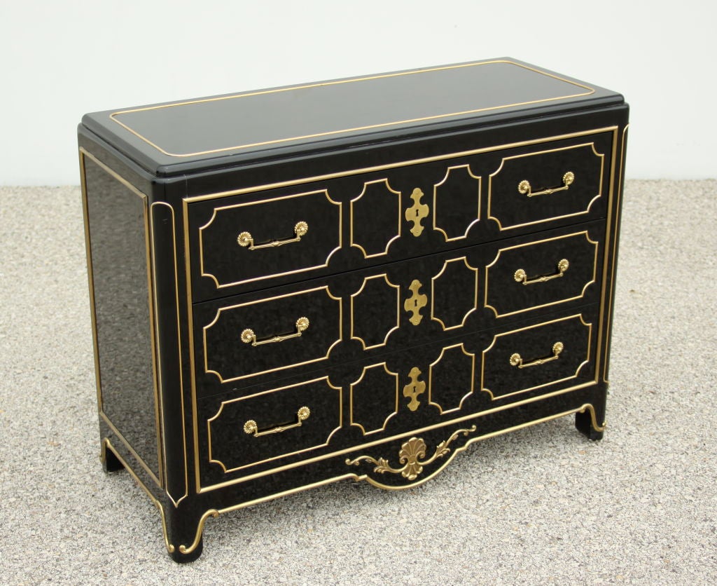 Lacquered chest of drawers in dark navy with brass raised details.