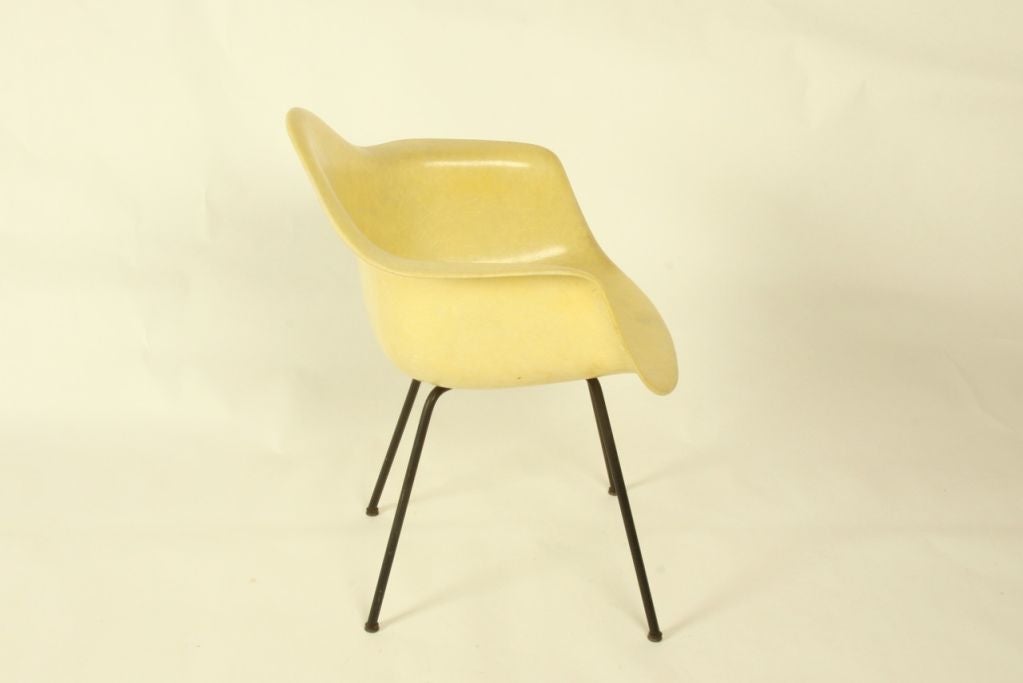 Eames Zenith shell armchair, rope edge and black enameled metal legs in x pattern underneath, pale yellow fiberglass shell, fiberglass is free of chips, some age related wear to the shell but overall a good example of an early Eames chair.