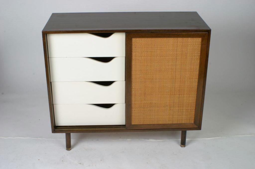 Harvey Probber two-door cabinet with cane sliding doors, drawers on one side, shelf on the other, brass sabots on legs.