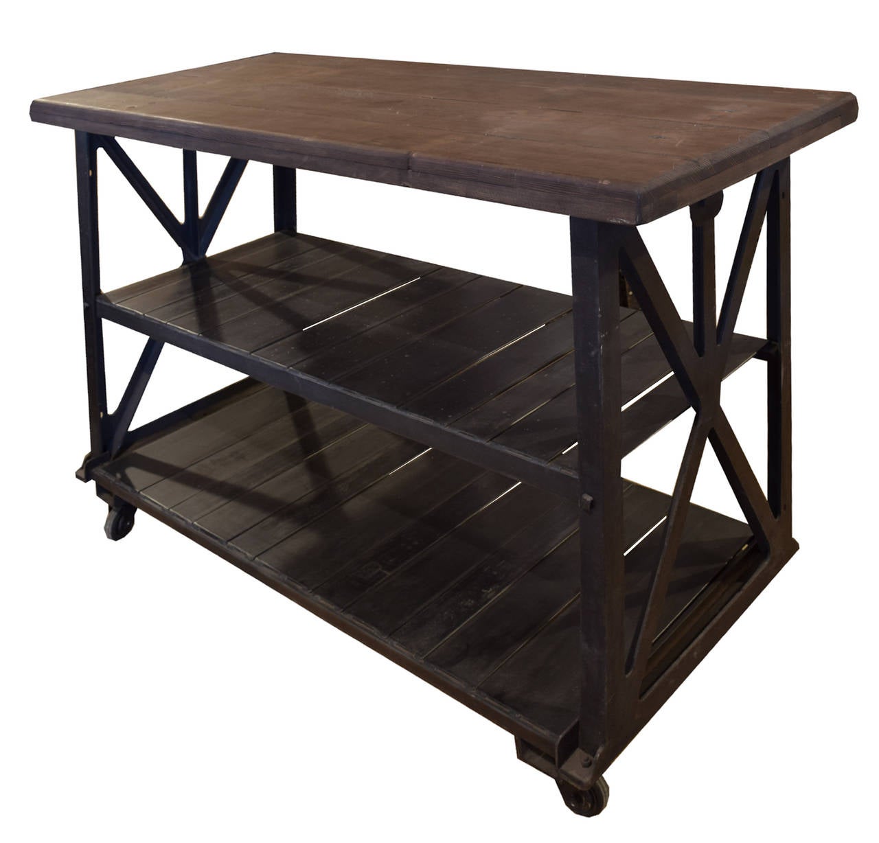 An American Industrial table with a metal frame with two shelves, a wood top and iron casters.
