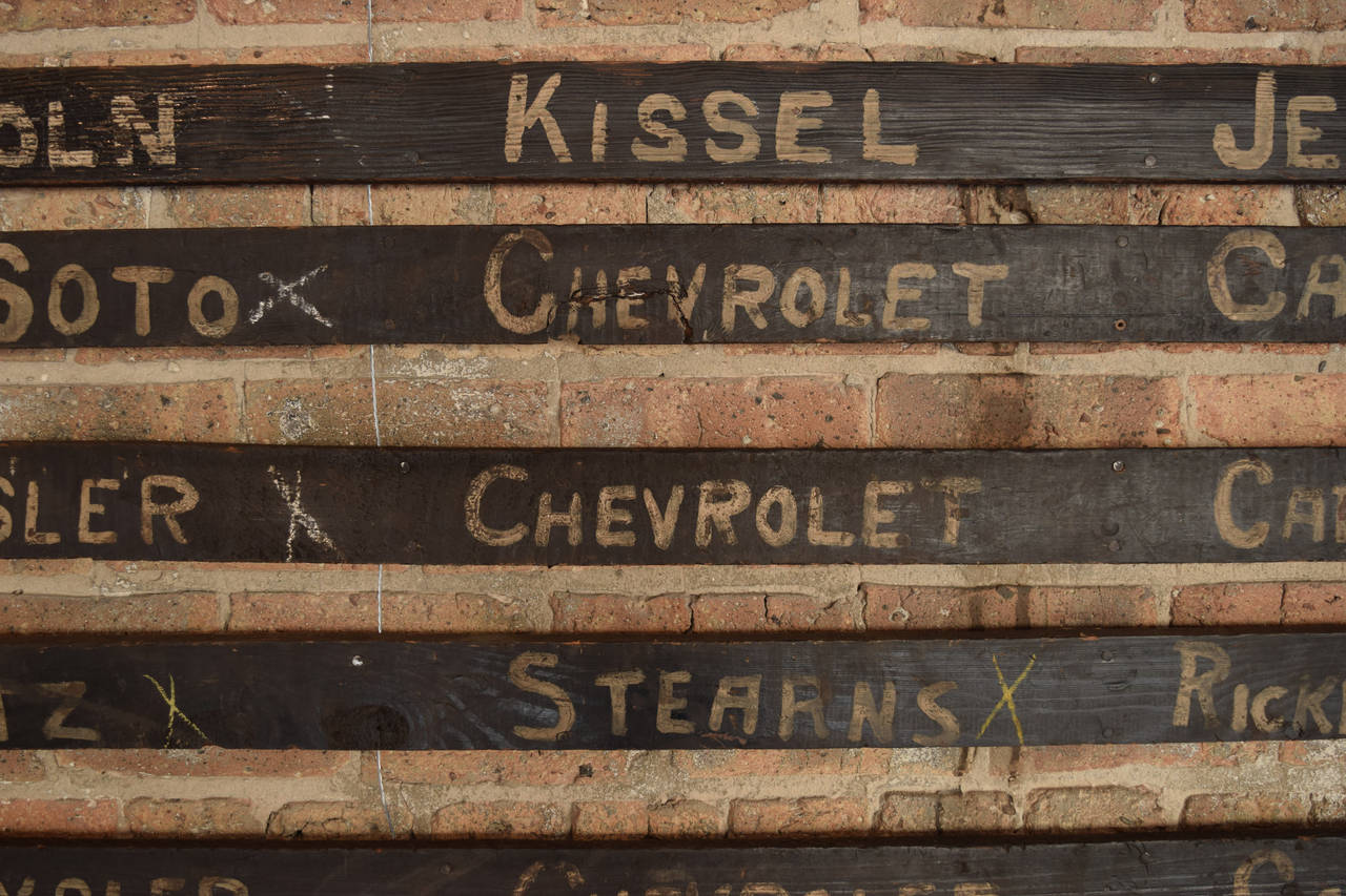 13 circa 1930 wood signs painted with automobile manufacturer names, used to identify car parts.

Dimension listed is the full size of all 13 hung as a group.