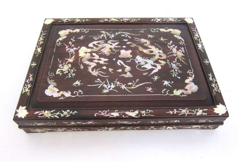 A beautifully crafted Chinese box inlaid with mother-of-pearl with bat, dragon and floral motifs, lined in silk.