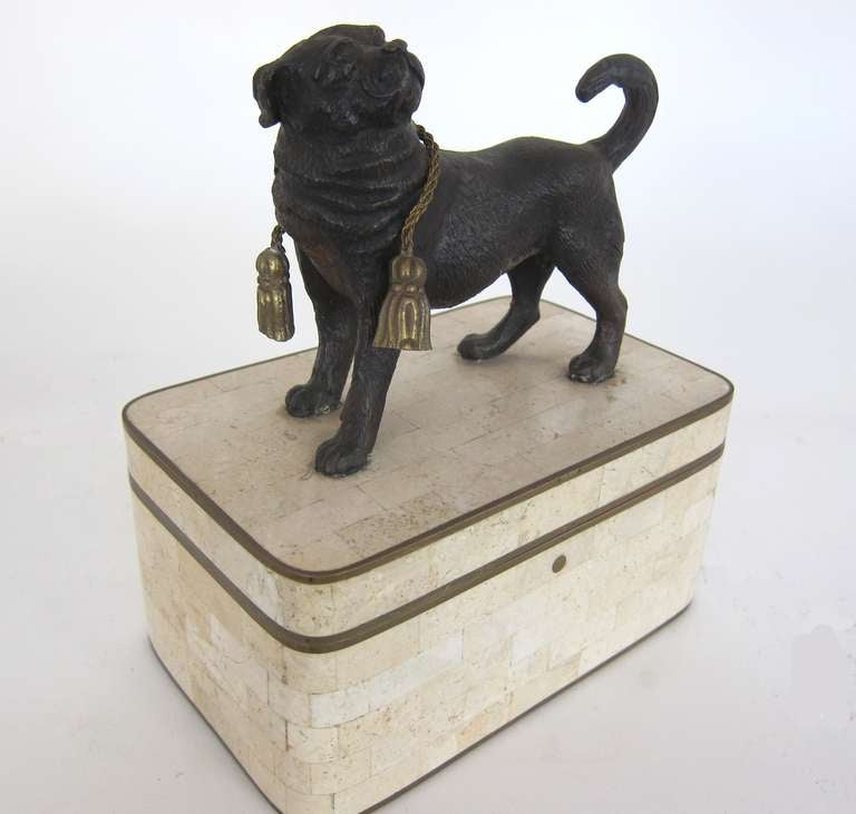 The stone clad figural wooden BOX having stone cut tiles in cream/white, trimmed in brass with a patined bronze PUG DOG ato, over his back is a bronze braided collar  which is loose 