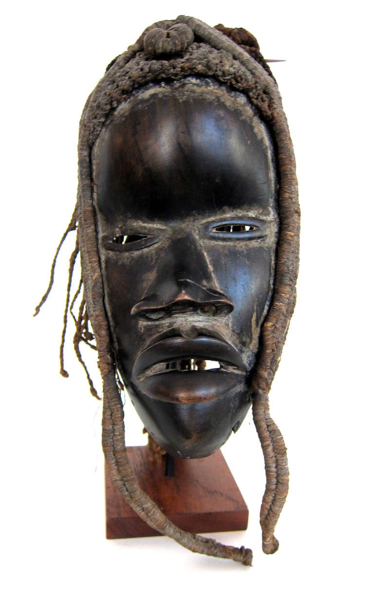 A carved African mask from the Dan tribe located in the Ivory Coast. The mask is carved from African hardwood and adorned with braided human hair.