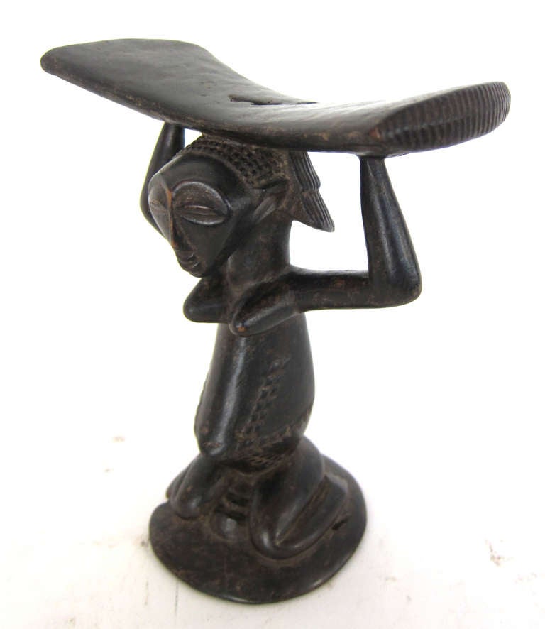 A well-carved African headrest of a woman holding a tray from the Luba tribe. The Luba peoples occupy a land of rivers and savanna in the southeast of what is today Democratic Republic of Congo. Purchased 1988 Provenance New Orleans Andy Antippas.