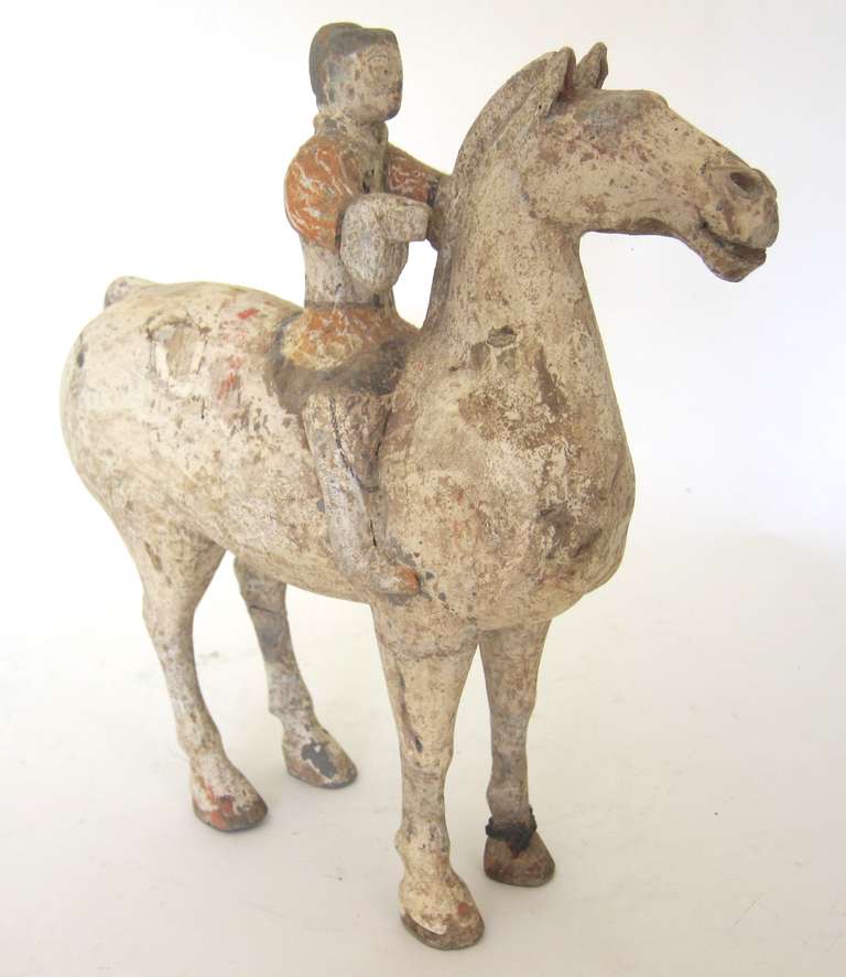 A superb Western Han Dynasty Horse with Rider with a good deal of the original paint remaining. Rider seated astride his horse, the soldier's hands
and horse's mouth with holes where a leather bridle and reins would once have been held.