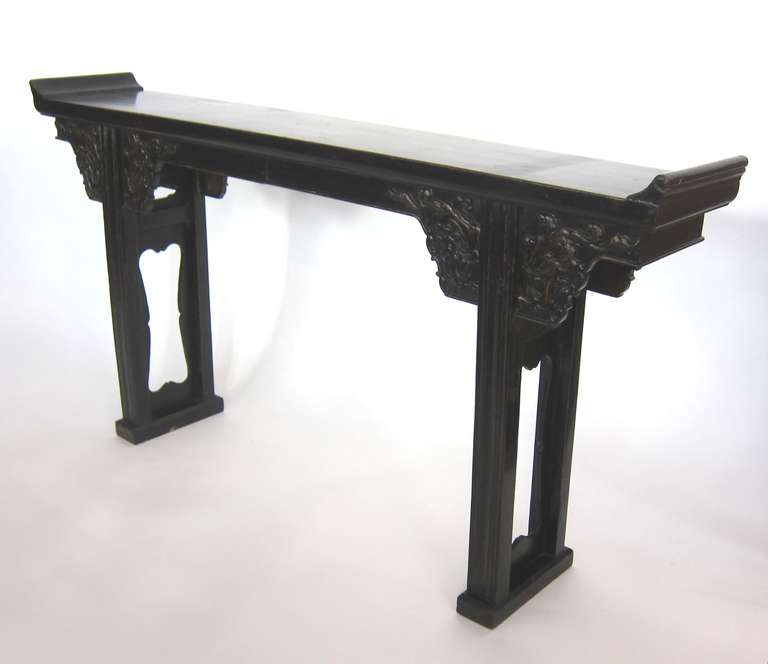 Well proportioned Chinese altar table with the original black lacquer. Beautiful carvings of stylized dragons on the apron. Great patina. Chinese Elmwood crafted with traditional mortise and tenon joinery. Two legged Atlar Tables are most desired.