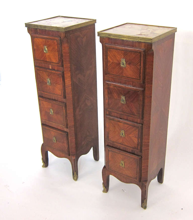 A pair of early 18th century French Petite Side Commodes with brass gallery and marble tops. Each with 4 drawers. Traditionally crafted with marquetry dove tail.