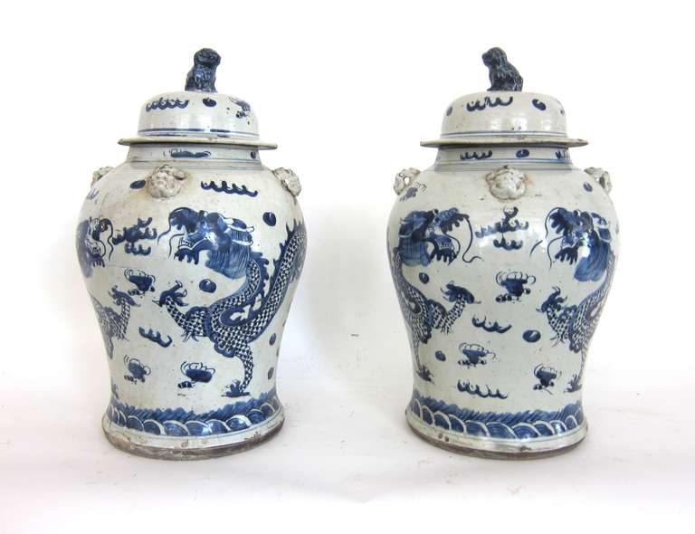 A beautifully painted pair of Chinese blue and white ceramic general jars. Exquisitely painted dragons and cloud motifs with a Foo Dog on each lid. Original lids.