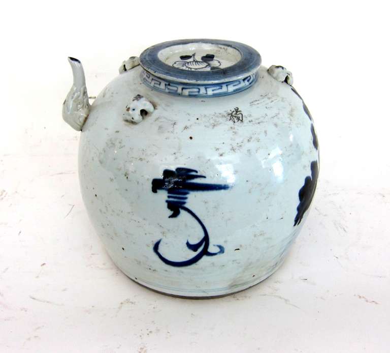 This Chinese Extra Large Tea Pot is hand painted blue on white.  It is signed by the artist having a flower design to the front.  Hand through pot and original lid.
Also having 3 dog heads to the top of the pot which a rope would have been in each