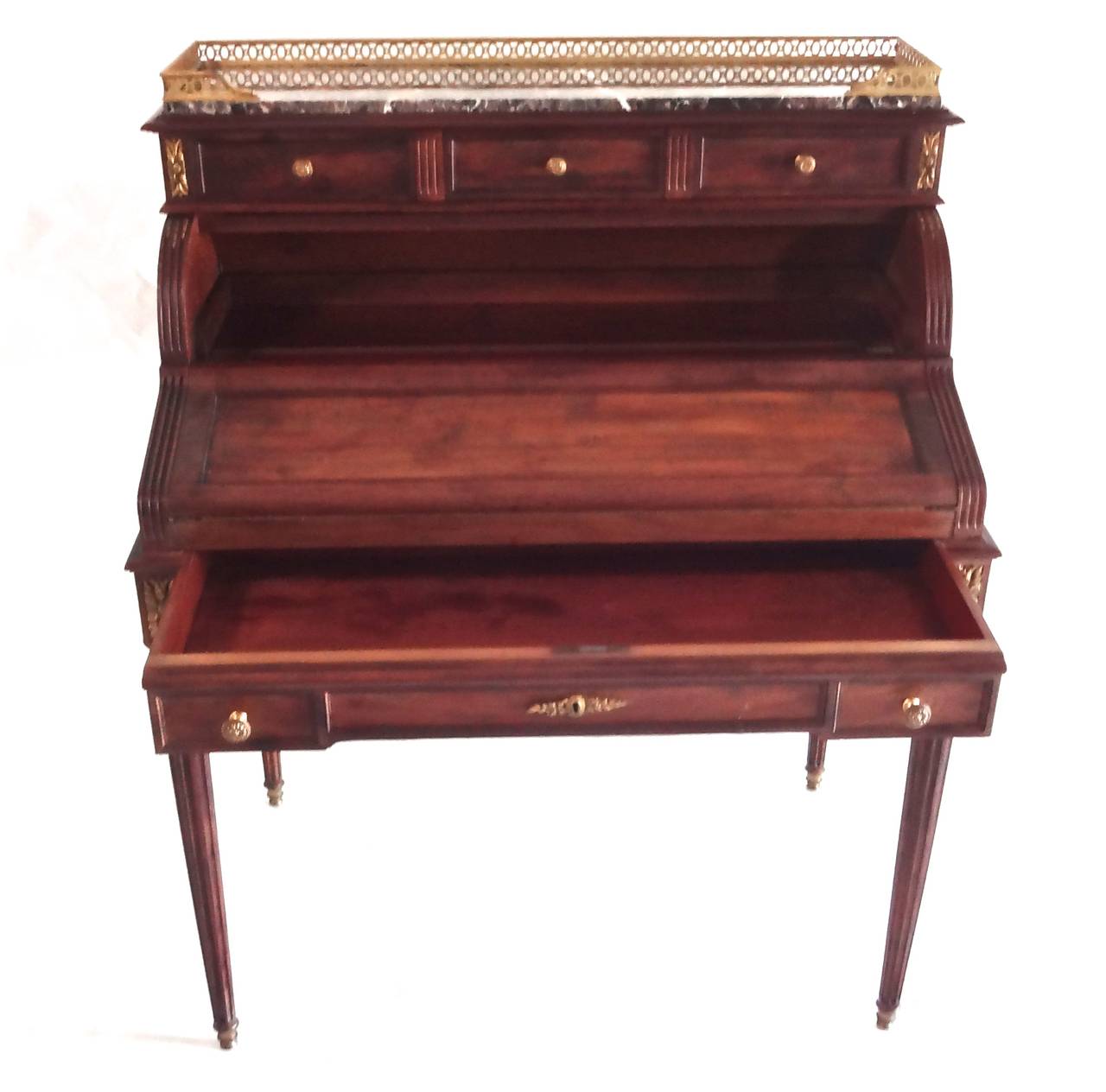 A French Louis XVI style mahogany mechanical cylinder writing desk with grey marble top, brass gallery and trim with 6 drawers. As the frieze drawer opens it triggers the opening of the mechanical writing surface covered in green felt blotter with