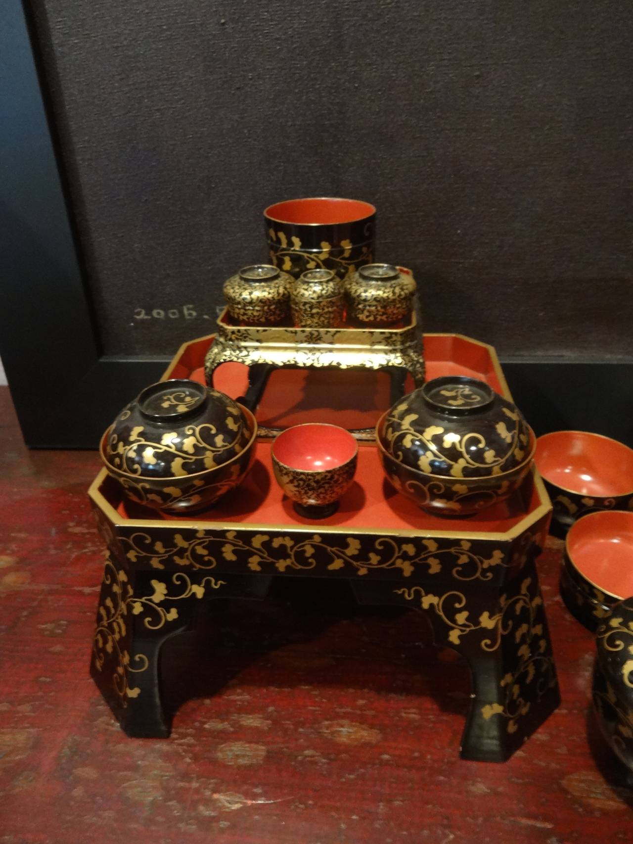 A Japanese gilt, black & red lacquer ware child's 46 piece tea set (includes lids) - 2 tables & stands, various bowls, plates, cups, etc. Largest piece measures 8.5 x 8.5 x 4 high.