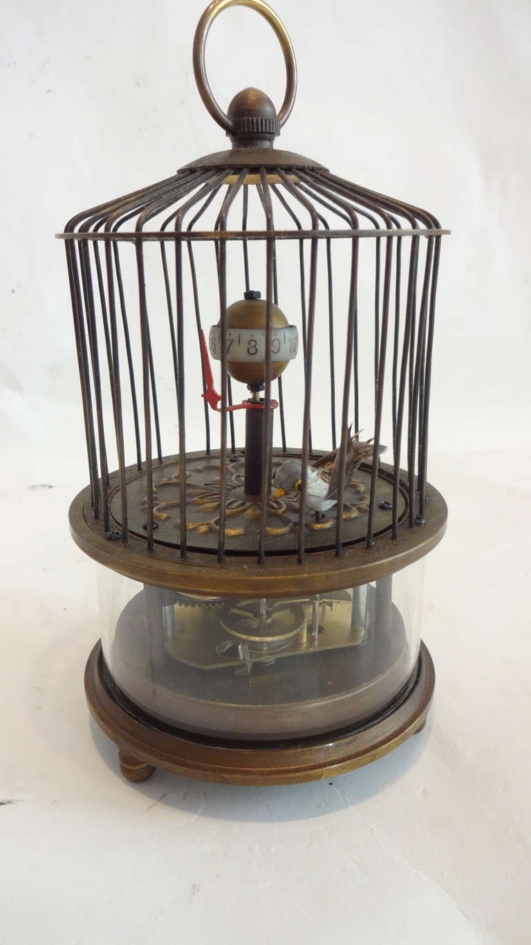 This is an unusual and interesting piece. The brass cage has a bird with feather on it which moves as the clock (the ball) moves around.  The red pointer tells the time.  Having 3 ball feet and an attached key for winding.