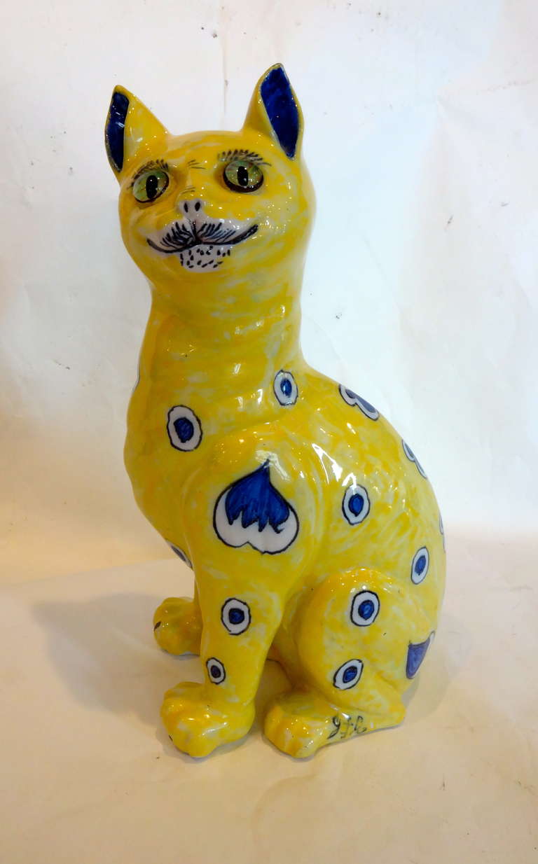 A Faience cat with whimsical indigo motifs on yellow ground blue hearts with glass eyes, signed E. Galle Nancy (1846-1904)