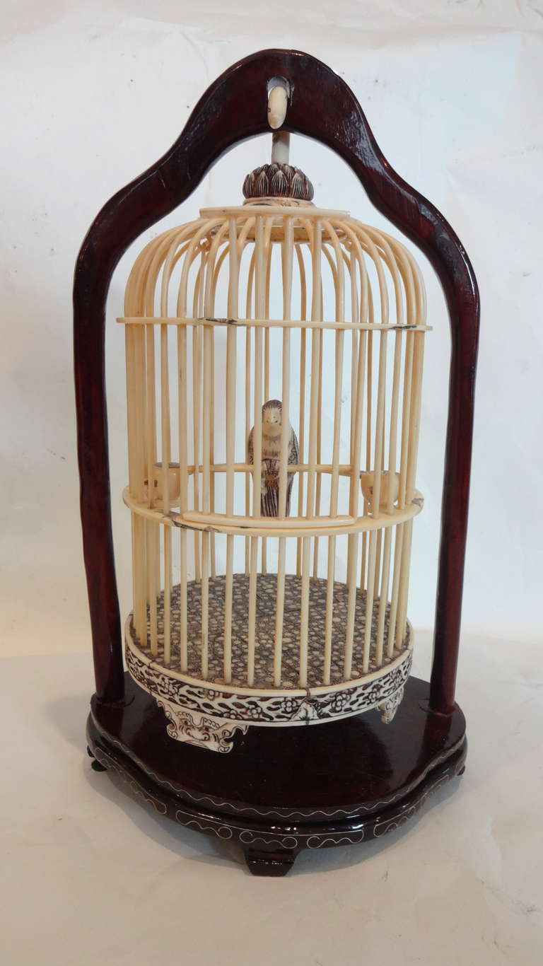 A Chinese carved birdcage with incised decoration, hand carved, polychrome suspended from a hardwood stand, signed