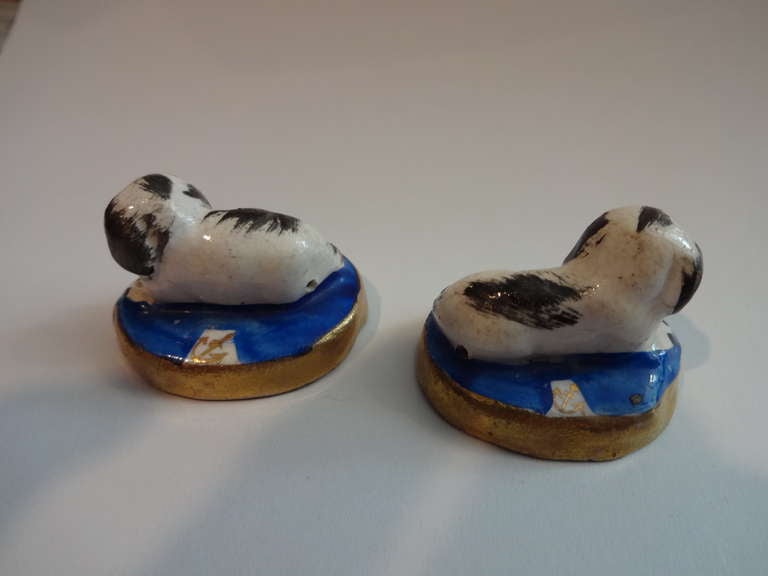 The pair of Miniature Staffordshire Spaniel DOG Statues are English depicting reclining dogs on blue pillows having the gilt anchor mark at the back of each (see picture...) gilt trim