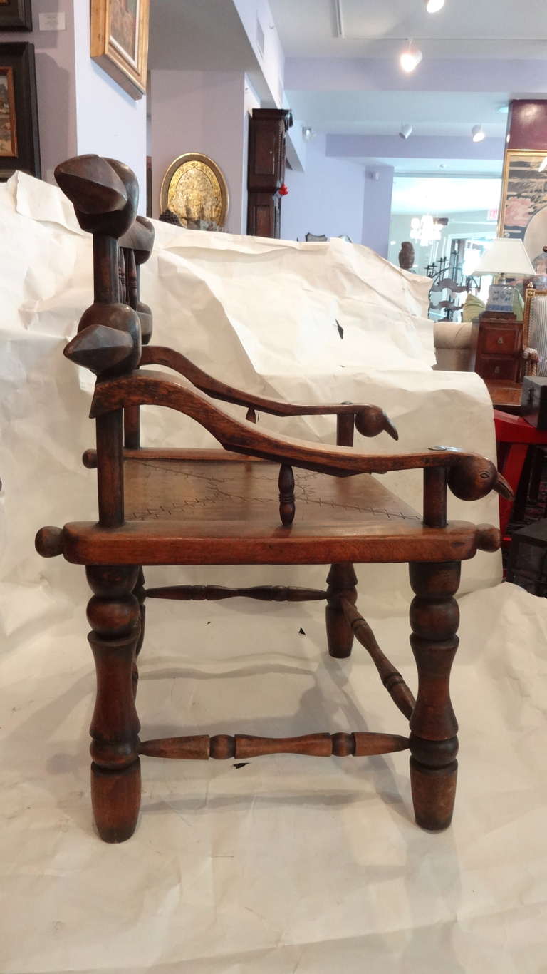 A pair of African arm chairs, King and Queen, possibly oak, with a geometric carved design on the seat and carved bird heads at the end of the arms