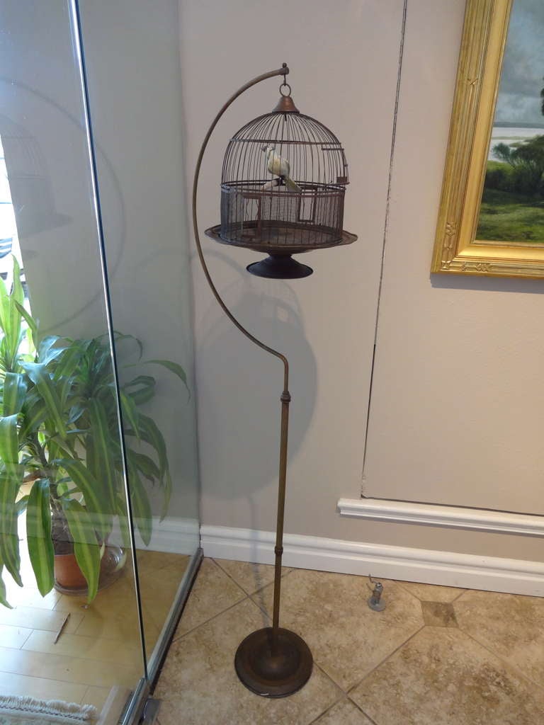This American bird cage and stand are made of brass and were mfg. by Hendryx, the cage may also sit on a surface.  With weighted stand and spring door ( 2 items - bird cage and stand. ) Cage is 15