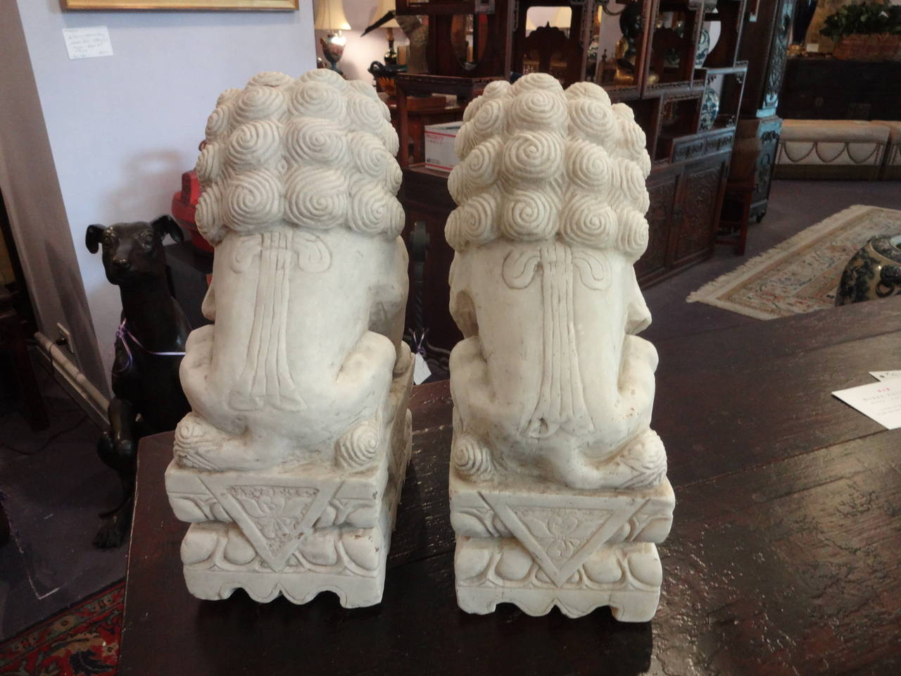 A pair of Chinese finely carved solid white marble foo dogs (guardian temple lions), female with cub under paw and male with ball under paw, mounted on rectangular plinth.