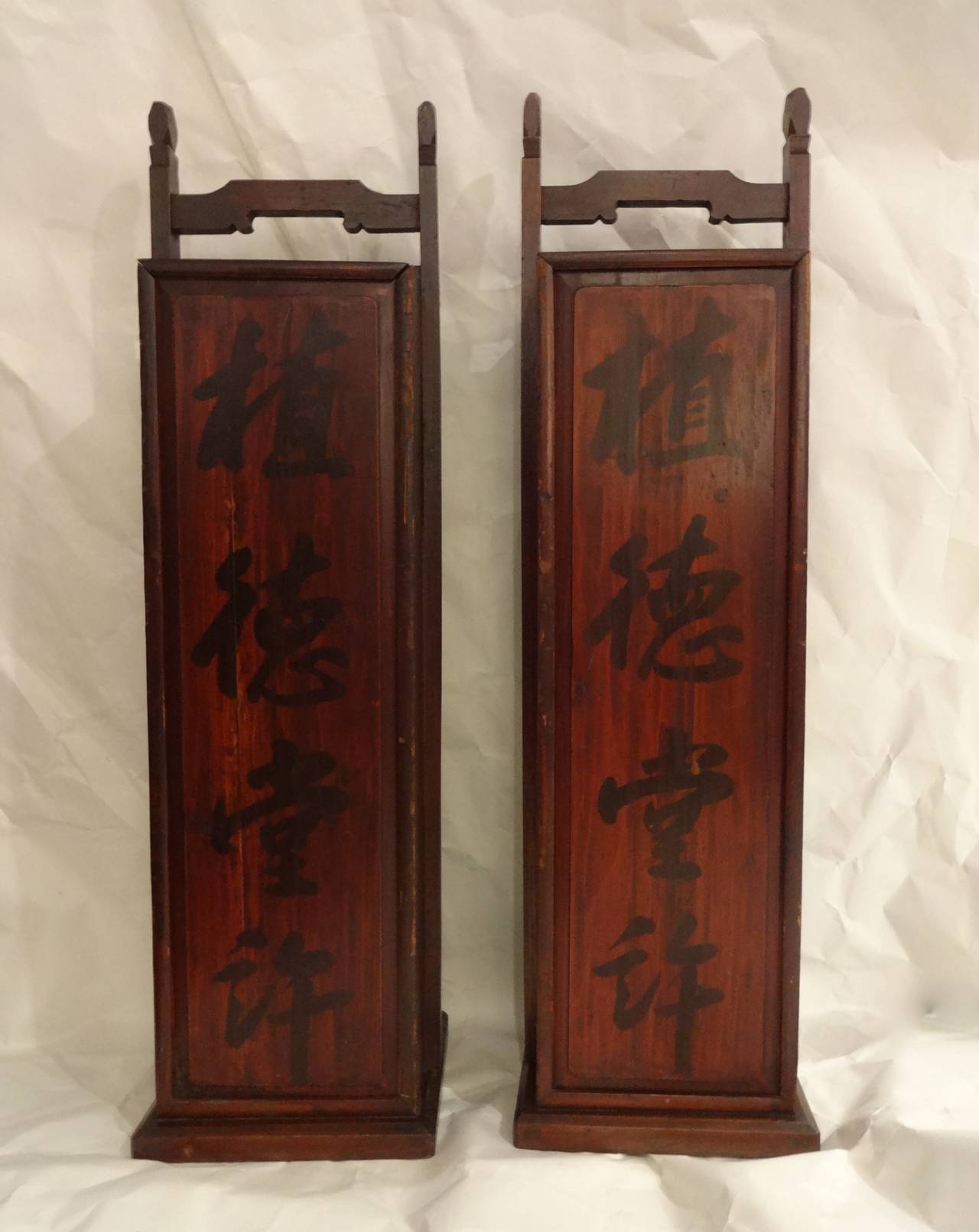 A pair of Chinese scroll cases with lift top doors, black calligraphy.