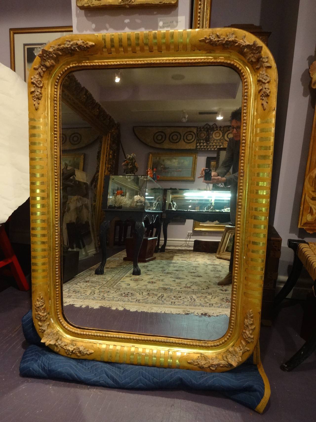 A French Empire carved and gilt wood mirror with rounded corners. Frame has hand carved floral relief on all four corners.
