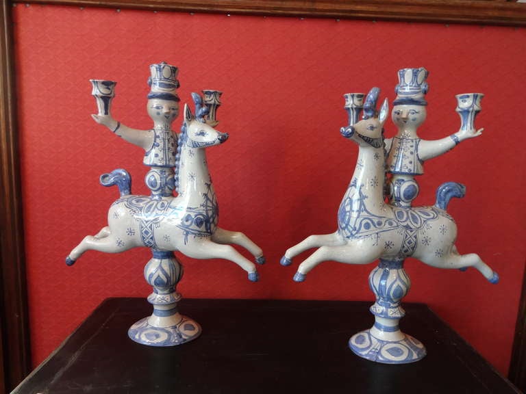 This pair of Bjorn Wiinblad CANDLESTICKS are a pair of man wearing top hats and holding 2 candleholders each riding galloping horses, hand painted marked on the bottom.