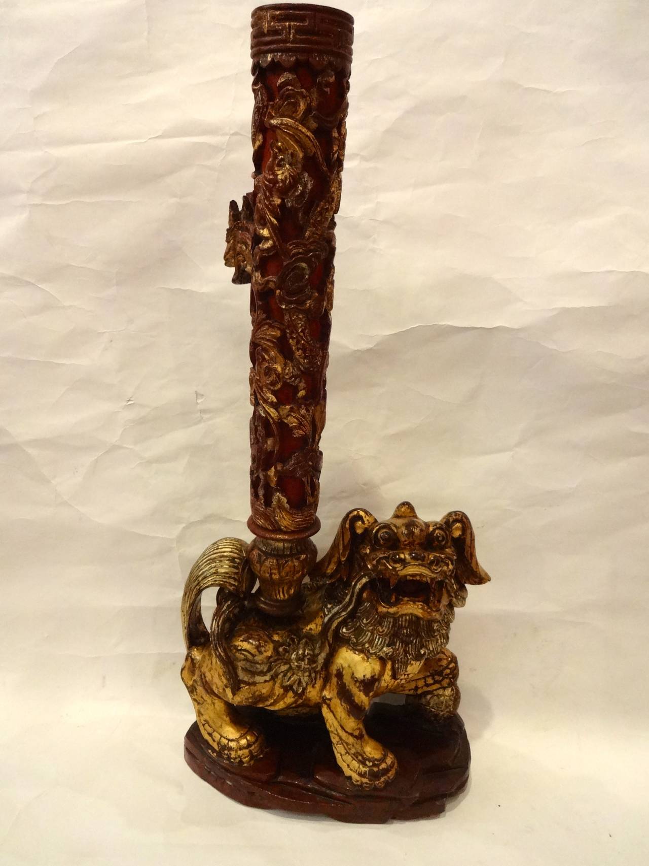 A Chinese hand carved gilt wood candlestick with dragon mounted on foo dog