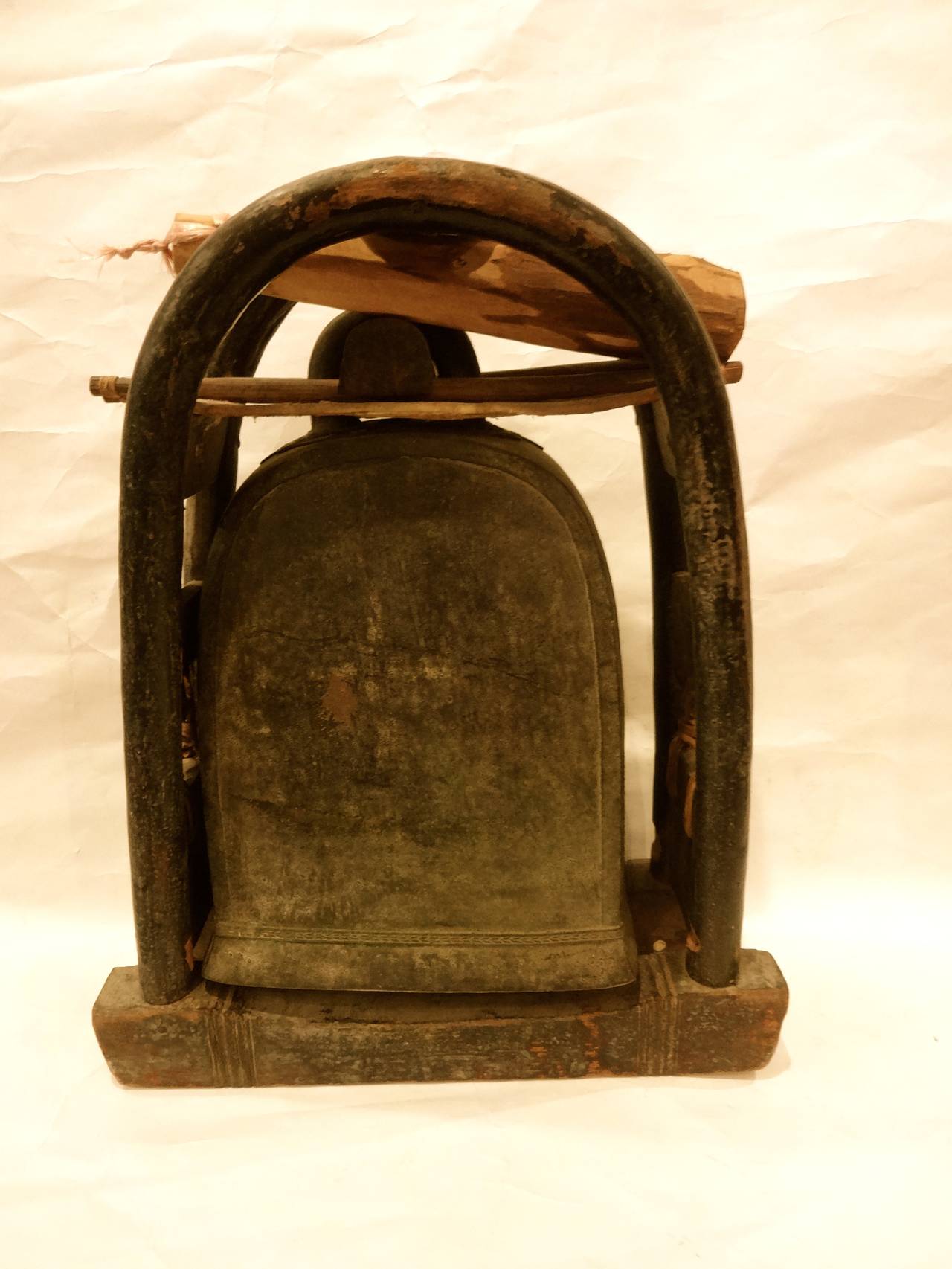 An antique Burmese bronze elephant bell in hand made wooden and leather holder with wooden striker