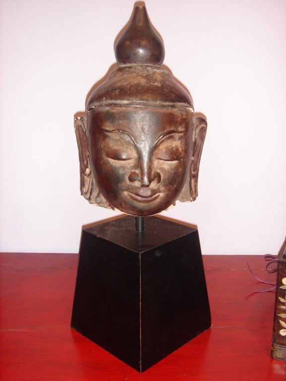 This Ava Style Burmese Buddha Head on wooden stand is made of sandstone and than brownish lacquered and in the Ava style. It has a wonderful face.