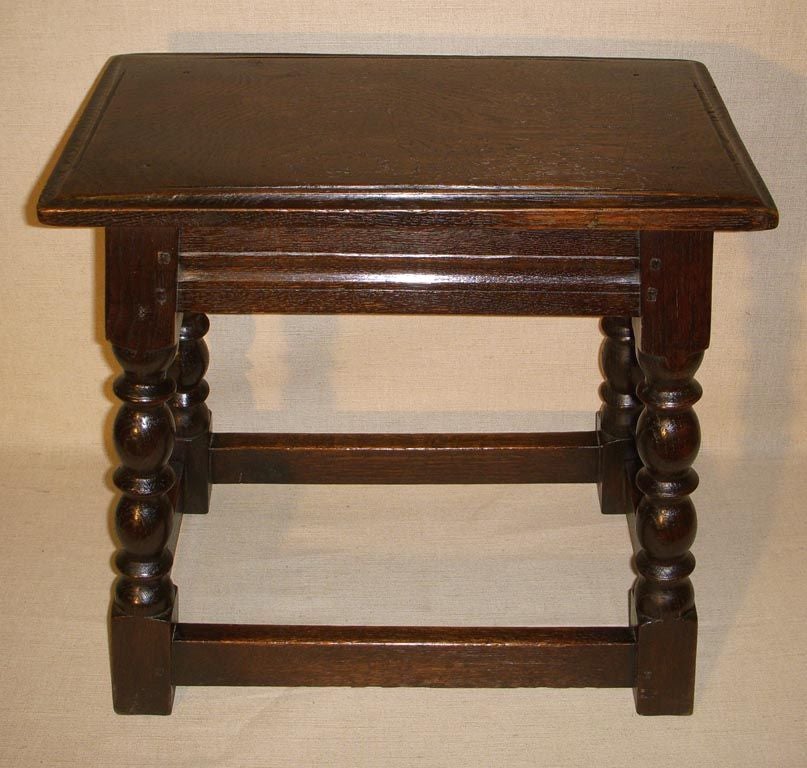 Jacobean Revival Carved Oak Joint Stool with Turned Legs Joined by a Box Stretcher Base.  England, Late 19th/Early 20th Century.<br />
<br />
18 inches wide x 10 inches deep x 18 inches high