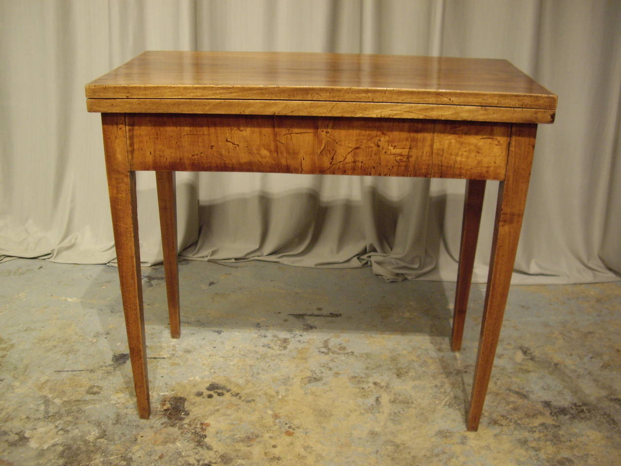Very nicely restored walnut card table that turns and makes a table with center base on four legs.