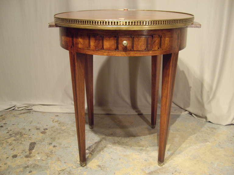 Louis XVI style inlaid bouillotte table with table top insert leather on one side and inlaid on the other.  Table has brass gallery around marble top. Two candlestick sides on either side and two drawers on either side. Very nice detail work with